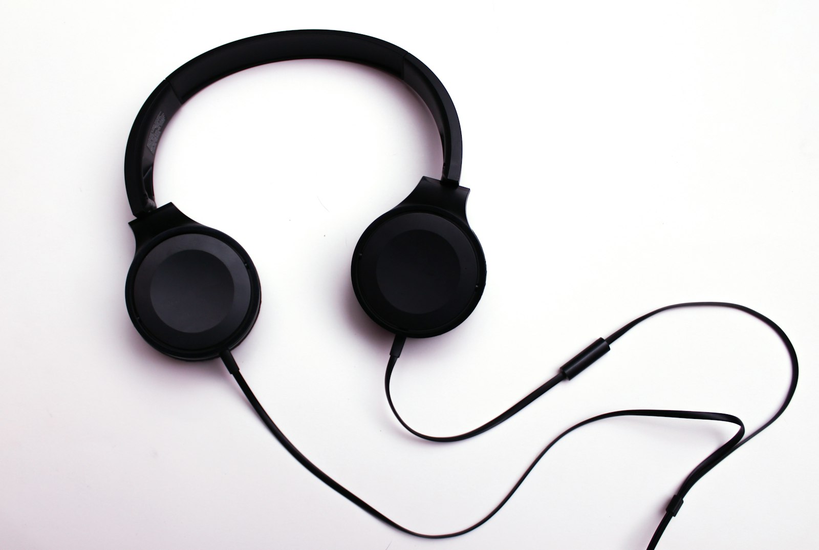 Black on-ear headphones with a long cable and an inline control on white.
